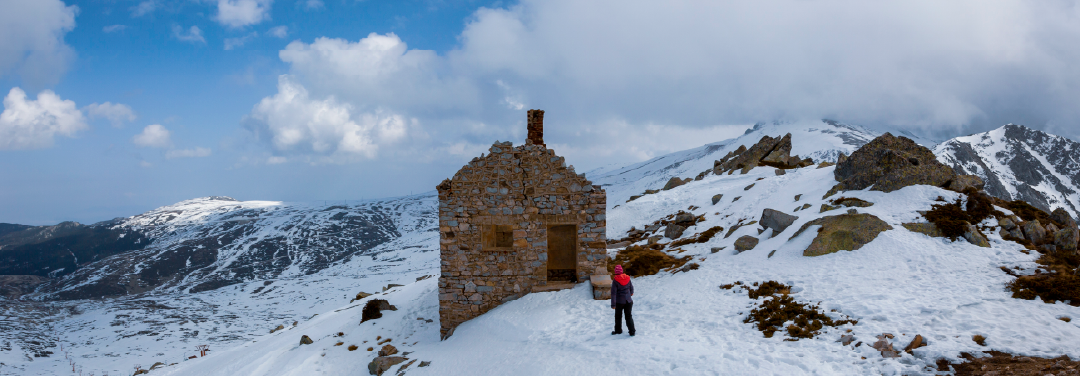 Remote stone mountain cottage surrounded by snow-covered hills and misty landscapes, offering a peaceful escape for a digital detox.