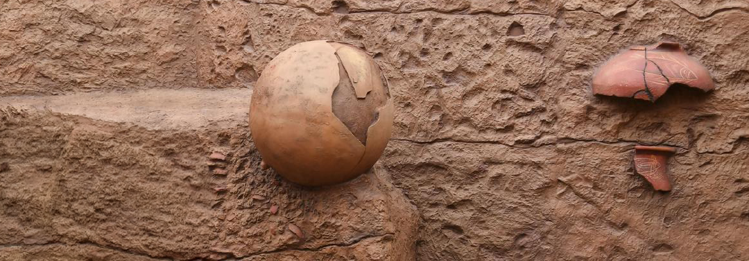 Ancient earthenware pottery and archaeological artefacts displayed on excavated soil, representing the Keeladi archaeological discoveries in Tamil Nadu.